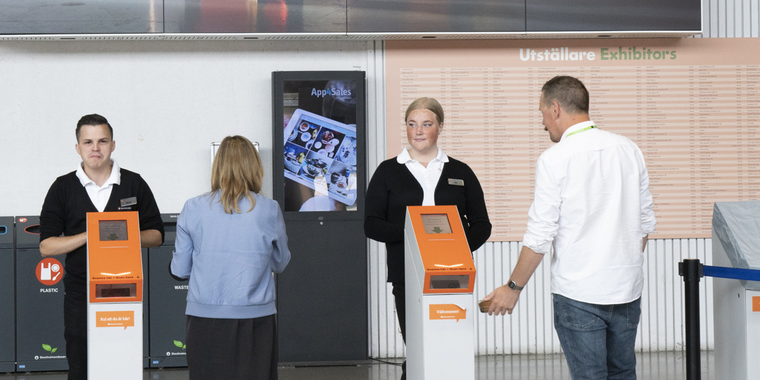 En grupp människor som går längs en trottoar mot Stockholmsmässan. 